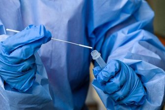 Eine Krankenschwester steckt ein Abstrichstäbchen in die Flüssigkeit eines Corona-Schnelltests.