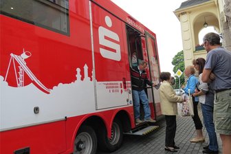 Pannen plagen den „Zaster-Laster“: Wie es für Kunden der Sparkasse Vogtland weitergehen soll - 16 Orte fährt die Mobile Filiale der Sparkasse Vogtland an, im Bild macht sie Station in Erlbach. Seit Monaten gab es jedoch mehrfach technische Probleme. Am Montag soll der „Zaster-Laster“ wieder starten.