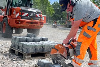 Parkplatzbau am Erzgebirgsklinikum: Warum die Baustelle in Zschopau fast ein Dreivierteljahr brachliegt - Vorarbeiter Andreas Wächtler schneidet auf der Baustelle neben der Alten Marienberger Straße Betonsteine.