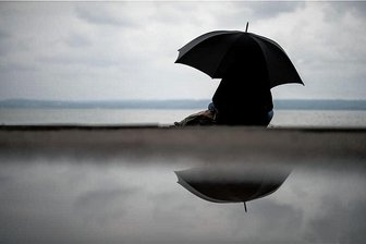 Performance zum Stein: Ab sofort werden Ticketpreise erstattet - Eine Frau sitzt für dieses Symbolbild bei verregnetem Wetter im Freien. Das Wetter spielte den Organisatoren der Performance zum Stein übel mit.