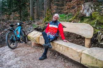 Pfiffige Idee im Erzgebirge: Klimastämme speichern Kohlendioxid - Stefan Bauer, der gern mit dem Fahrrad auf dem Erzengelweg fährt, nutzt die neue Bank zur Rast.