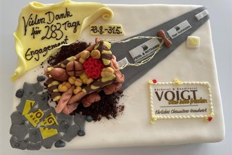Plaback-Chef steigt bei Bäckerei Voigt in Chemnitz ein: Insolvenzverwalter bekommt Torte als Dankeschön - Diese Torte haben Mitarbeiter der Voigt-Bäckerei an Insolvenzanwalt Tobias Hohmann übergeben. Rechts ist das aktuelle Logo des Traditionsbetriebes zu sehen.