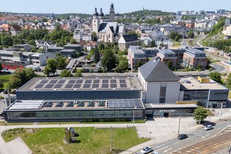 Plauener OB stellt millionenteuren Bad-Anbau nochmal auf den Prüfstand: So lautet die Entscheidung - Das Stadtbad an der Hofer Straße vor der Plauen-Kulisse. Das Bad wird nun ausgebaut.
