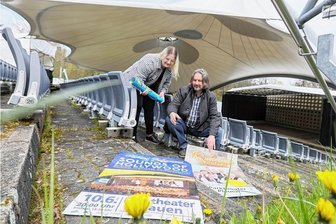 Plauener Parktheatersaison 2023: Schlager, Volksmusik, Rock und ein umstrittener Kabarettist - Vor der Kulisse des Plauener Parktheaters mit seinem imposanten Zeltdach präsentieren Lisa Hufenbach und Parktheater-Chef Ronny Bley Plakate mit einigen der Veranstaltungshöhepunkten der diesjährigen Saison. 