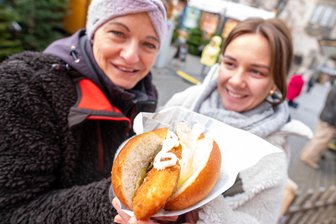 Plauener Weihnachtsmarkt im Preis-Check: Was müssen Besucher für Roster, Glühwein und gebrannte Mandeln bezahlen? - Backfisch im Doppelbrötchen aus Magwitz für sechs Euro ließen sich am Freitag Susann Teuchert und Emelie Krannich (rechts) schmecken.