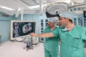 Plötzlich Hirnblutung: Wie ein neues Verfahren einem Sachsen das Leben rettete - René Weigel aus Jahnsdorf sieht im OP-Saal der Neurochirurgie des Klinikums Chemnitz das erste Mal die Bilder aus der Diagnostik seiner Hirnblutung. Neurochirurg Dr. Ararat Minasyan zeigt, wo der Katheter platziert wurde.