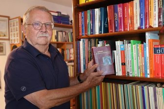 Professor verabschiedet sich mit tschechischen Klassikern - Reiner Neubert in seiner hauseigenen Bibliothek. In den Händen ein Werk von Jan Neruda. 