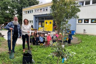 Projekt Zukunft: Warum Gerüstbauer Kai Flößner in der Kita „Spielhaus“ in Flöha einen Apfelbaum pflanzt - Baumpflanzaktion Mittelsachsen Award mit Kai Flößner und Kerstin Kunze von der Wirtschaftsförderung. Janine Löser und Michele Schulze mit den Kita-Kindern beobachten die Pflanzaktion.