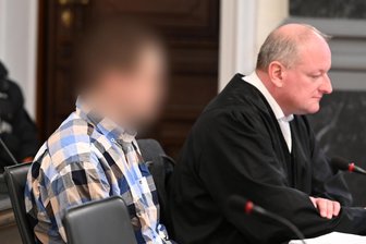 Prozess wegen Dreifach-Axtmord im Vogtland: „Es waren Schreie, wie ich sie noch nie in meinem Leben gehört habe“ - Ein 28 Jahre alter Mann aus Tirpersdorf ist wegen dreifachen Mordes angeklagt. Im Gerichtssaal sitzt er neben seinem Rechtsanwalt Andreas Baumann.