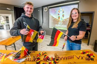 Public Viewing im Erzgebirge: Tipps zum Gruppen-Gucken zur Fußball-EM - Beamer und Leinwand sind installiert, die Biertischgarnituren stehen. Robin Pahner (links) und Cheyenne Worotnik dekorieren den Saal des Jugendzentrums im Olbernhauer Ortsteil Kleinneuschönberg für das erste Public Viewing am Freitagabend.