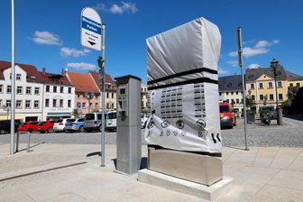 Rätselraten auf dem Markt in Glauchau: Was wird hinter Verpackungsmaterial versteckt? - Direkt neben dem Parkautomaten steht neue, bisher noch verpackte Technik. Sie wurde von der Stadt angeschafft.