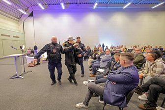 Rauswurf von rechtsextremen Influencer in Meerane: AfD will Vorfall im Stadtrat zum Thema machen - Mitarbeiter des Ordnungsamtes führen den Influencer aus der Halle.