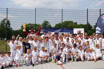 RB-Maskottchen Bulli bringt sogar den DFB-Pokal mit zum Feriencamp - Zum RB-Feriencamp gehört es auch, dass alle Kinder ein personalisiertes Trikot mit passender Hose und Stutzen bekommen. Auch Trinkflasche sowie Sportbeutel mit RB-Logo gibt es für die jungen Fußballer. 