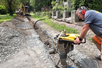 Reichenbach: Gießwasserleitung auf dem Hauptfriedhof wird ausgewechselt. - René Weller (vorn) und Kay Walter (im Bagger) von der Firma Förster Haustechnik, Tiefbau- und Rohrleitungsbau aus Hartmannsdorf auf dem Hauptfriedhof in Aktion.