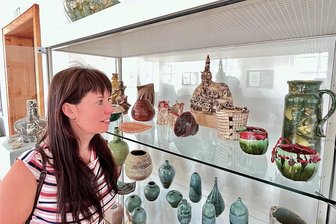 Reichenbach: Wie die Keramikwerkstatt dem Deko-Kitsch die Stirn bietet - Cornelia Meinel, die in ihrer Jugend selbst in der Keramikwerkstatt aktiv war, vor einer der Vitrinen in der Ausstellung „Ton-Theater“. Besonders gefiel ihr das Lichterhaus von Martin Werlich (hinten Mitte).