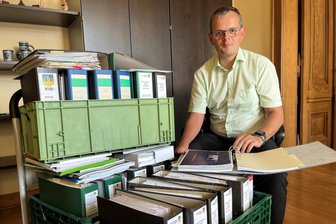 Reichenbach: Wofür das Stühlerücken im Rathaus gut sein soll - Tobias Keller in seinem Büro mit einem ganzen Wagen voller Akten zum Thema Bundeskältekompetenzzentrum.