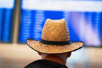 Reisebranche plant mit der Unsicherheit - Ein Mann mit Strohhut schaut beim Warten auf eine Anzeigetafel. Nach einem erneuten Umsatzeinbruch im zu Ende gehenden Tourismusjahr rechnen Veranstalter und Reisebüros damit, frühestens 2023 in etwa das Vorkrisenniveau zu erreichen.