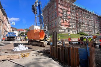 Riesenloch in Reichenbach: Fertigteil-Schacht schwebt in die Baugrube - Ein Schachtfertigteil schwebt am Bagger-Ausleger in die Baugrube mitten auf der Kreuzung ein.
