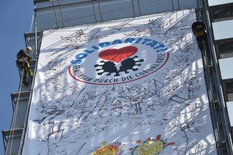 Riesenposter ruft zu Solidarität in Corona-Krise auf -
