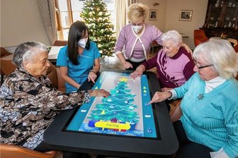 Riesentablet: Wie Marienberger Senioren das Internet erkunden - Barbara Lauckner-Kempf (Mitte) schaut Ergotherapeutin Marleen Hammer (2. v. l.) und den Bewohnerinnen Christa Hofmann (l.) sowie Anneliese Hammer und Helga Bielitz (v. r.) bei der Beschäftigung am neuen Riesentablet über die Schultern.