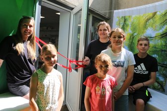 Rodauer Kinder freuen sich über einen neuen Raum für kreatives Hobby - Symbolische Einweihung des neuen Raums mit Schleifenband: Christina Michel (links) und Ivonne Prager mit den Kindern Matilda, Laura, Maike und Konrad.