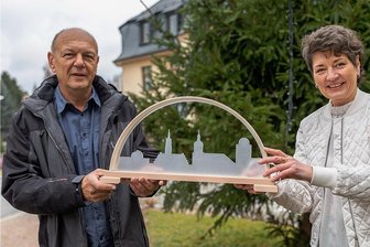 Rodewischer Ansichten unterm Bogen - Werkstattleiter Andreas Müller übergibt Bürgermeisterin Kerstin Schöniger einen der Schwibbogen mit Motiven der Stadt, die aus satiniertem Plexiglas gearbeitet sind. 