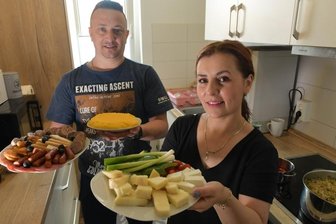 Rumänische Mitarbeiter bei Saxonia sind im neuen Zuhause auf dem Wasserberg angekommen - Elena und Alin Cracana aus Rumänien haben in ihrer Wohnung zu Mittag gekocht. Elena bringt einen gemischten Teller mit Käse zum Tisch, Alin einen Slanina-Wurstteller und Màmàligà-Kuchen.