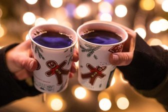            Zwei Besucherinnen eines Weihnachtsmarktes stoßen mit Glühwein an.