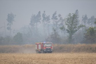 Sachsenburg: Feuerwehrleute aus Mittelsachsen löschen bei Waldbrand in Gohrischheide - Ein Einsatzfahrzeug der Feuerwehr fährt vor dem Waldbrand in der Gohrischheide.