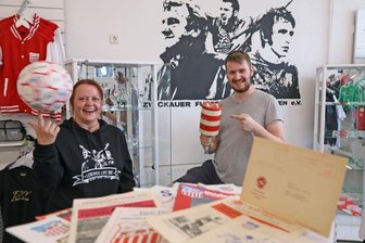 Sachsenring-Andenken zwischen VEB und Planwirtschaft - Kathrin Maneke und Chris Scheundel beim Aufbau der Ausstellung im FSV-Fanshop. Der Vereinsvorsitzende zeigt eine zu DDR-Zeiten gefertigte Rassel von Zwickau-Fan Kurt Mehlhorn. 