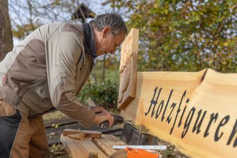 Sagenpfad im Erzgebirge bekommt Zuwachs: Schnitzer legen erneut Hand an - Mitglieder des Schnitz- und Krippenvereins Geyer haben am Sagenpfad eine Bank samt geschnitztem Relief aufgestellt. Zudem sind noch weitere Figuren geplant. Im Bild: Günter Schreiber vom Verein.