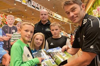 Sammeln wie bei Panini: Andrang beim Verkaufsstart in Markneukirchen - Die Kinder Aidon Ullmann (links), Avelyn Ullmann (Mitte) und Marlon Ullmann (zweiter von rechts) vom BC Erlbach gehören zu den Stickerstars, die im neuen Sticker-Sammelalbum vertreten sind. Sie schauen sich das Stickeralbum zusammen mit Andreas Meißner (hinten rechts) vom Edeka-Markt in Markneukirchen und Matthias Stock (rechts) vom BC Erlbach an.