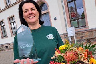 Sandy Vogel aus Grünberg erhält Preis: Mit Herz und Hand für die Dorfgemeinschaft - Sandy Vogel freut sich über den Generationen-Award, der demnächst einen Ehrenplatz in der ehemaligen Schule Grünberg (im Hintergrund) erhält.