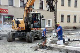 Sanierung des Elsterberger Kirchplatzes kommt voran: Ab wann kann der Verkehr wieder rollen? - Mitarbeiter der Weischlitzer Baufirma TIW verlegen Granit-Bordsteine für den künftigen Fußweg an der Kirche.