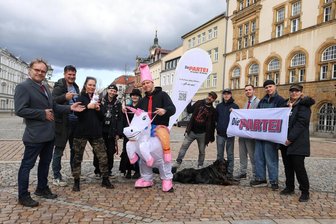 Satire-Partei haut wieder einen raus: Wiederansiedlung der Einhörner im Landkreis Zwickau gefordert - In Werdau auf dem Markt haben sich Mitglieder und Sympathisanten der Partei „Die Partei“ mit einem Plastik-Einhorn fotografieren lassen – aus gutem Grund.