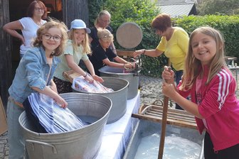 Sauerkraut und große Wäsche: Wie Kinder im Vogtland im Heimatmuseum Theuma in das Leben ihrer Urgroßeltern eintauchen - Sophie, Joline und Leonie (von links) bearbeiten die Wäsche mit Kraft und Ausdauer.