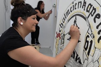Schalmeienkapelle Steinbach hofft noch auf kleine Jubiläumsparty - Beim Renovieren des Probenraums legten Mitglieder der Schalmeienkapelle Steinbach fleißig mit Hand an. Hier arbeitet Fränzy Lorenz am Wappen des Ensembles, hinten Anna-Lena Tippmann. 
