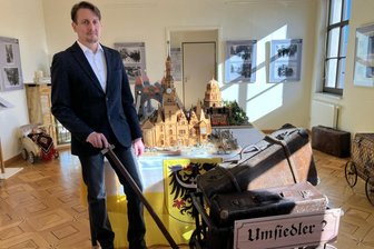 Schau zu Flucht und Vertreibung: Kurator aus dem Erzgebirge hat persönlichen Bezug zum Thema - Kurator Daniel Kostka bei einigen der Exponate, unter anderem vor Modellen von Gebäuden in Schlesien, die ein von Flucht und Vertreibung Betroffener später anfertigte.