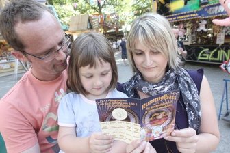 
              <p class="artikelinhalt">Stefanie und René Heering schauen sich mit Tochter Laura die Ermäßigungen an, die der neue Rummelpass bietet. Die Rabattkarte wird in diesem Jahr erstmals zum Stadtparkfest angeboten. </p>
            
