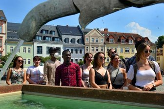 Schirm, Charme und Streuselschnecken - Auf dem Markt erfuhren die Studierenden aus Indien, Moldawien, Kamerun, Nigeria und dem Sudan Wissenswertes über das Rathaus, die Postsäule und die Marmeladentante genannte Brunnenfigur.