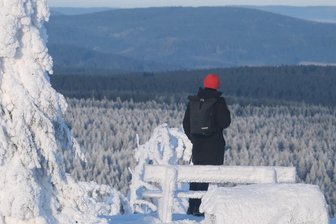 Schnee und Frost oder milderes Wetter? Das kommt jetzt auf Sachsen zu - Schöne Aussicht, aber frostig: Ein Spaziergänger auf dem vereisten Gipfel des Fichtelbergs.