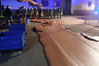 Schokoladenstrom auf Straße - Kein Zuckerschlecken für Feuerwehrleute - Einsatzkräfte der Feuerwehr stehen neben auf der Strasse ausgelaufener Schokolade. Ein Schokoladentank war bei einer Firma übergelaufen. Die Strasse wurde gesperrt, eine Tonne Schokolade musste von einer Fachfirma beseitigt werden.