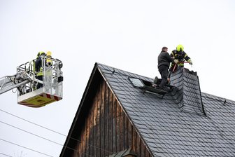 Schornsteinbrand im Erzgebirge: Straße während Einsatzes voll gesperrt - Für den Einsatz mussten die Feuerwehrleute aufs Dach, unterstützt wurden sie vom Lößnitzer Schornsteinfeger.