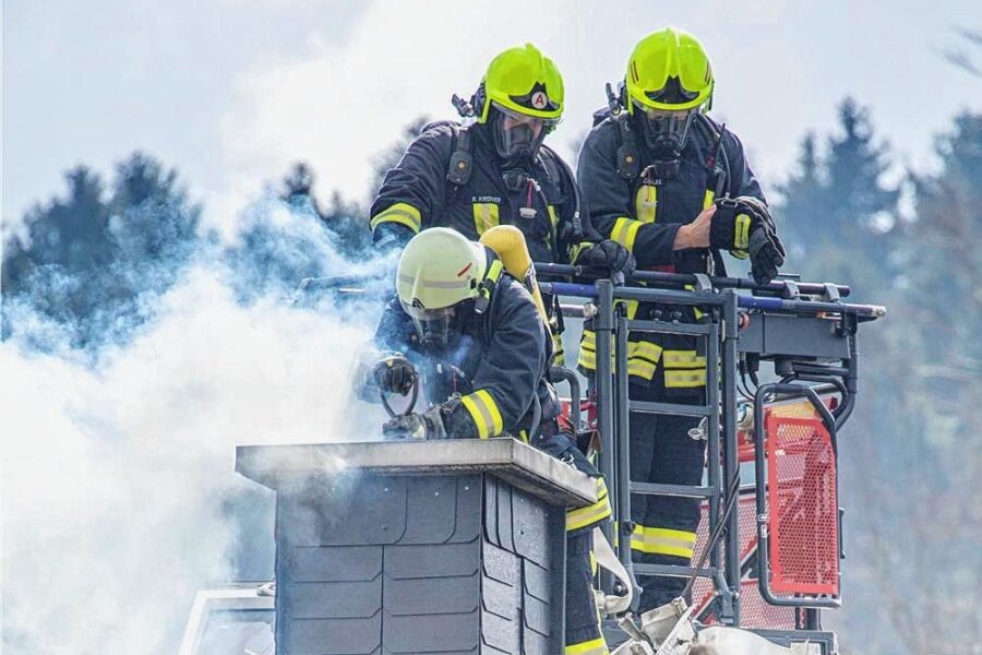 Schornsteinbrand: Sparen an falscher Stelle endet im Fiasko - Nur Feuerwehrleute unter Atemschutz können den brennenden Glanzruß lösen. Dafür setzen sie auch Split ein.  