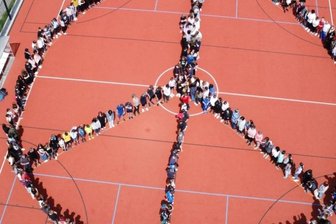 Schüler formen Peace-Zeichen - Mit einer Menschenkette haben Schülerinnen und Schüler der Oberschule Lichtenau zum Abschluss eines Projekttages ein riesengroßes Friedenszeichen auf dem Ballspielfeld gebildet.
