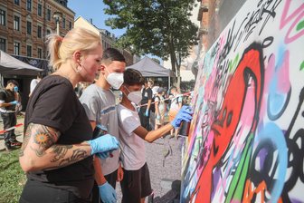 „Schule muss innovativer werden“: Wie eine Chemnitzer Oberschule ziemlich viel richtig macht - Marija Ambrazeviciute (Emesa) erklärt den Schülern Jaylen und Rodi (9. Klasse) das sprühen mit Spraydosen an einer Wand.
