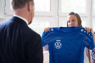 Schulsozialarbeit im Erzgebirge in Gefahr: Das bekam der Ministerpräsident im Zwönitzer Gymnasium zu hören - Schulsozialarbeiterin Franziska Illig überreicht Ministerpräsident Michael Kretschmer ein T-Shirt mit den Unterschriften zum Erhalt der Schulsozialarbeit.