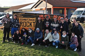 Schwarzbach rockt – zum zweiten Mal in kurzer Zeit - Die Organisatoren und ein Teil der Helfer von „Schwarzbach rockt“ am Werbebanner an der Geithainer Straße in Rochlitz. Sie freuen sich, dass es nun endlich losgeht.