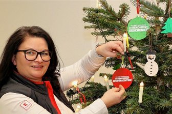 Schwarzenberg: Unternehmen helfen "Aktion Kinderherzen" beim Schenken - Im Eingangsbereich des Kauflands in Schwarzenberg steht der Weihnachts-Wünschebaum. Filialleiterin Ramona Elter zeigt eine der Kugeln, auf denen die Wünsche der Kinder aus den Kinderheimen stehen.