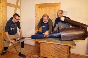 Schwarzenberger Schnitzer unter Druck - Roberto Lein (l.) ist als jüngstes Mitglied sehr engagiert und hat genügend Kraft, um die Löcher für die Metallhülsen in die neuen Beine der Figur zu bohren. Helmut Uhlig und Frank Schneider (r.) fixieren die Figur.